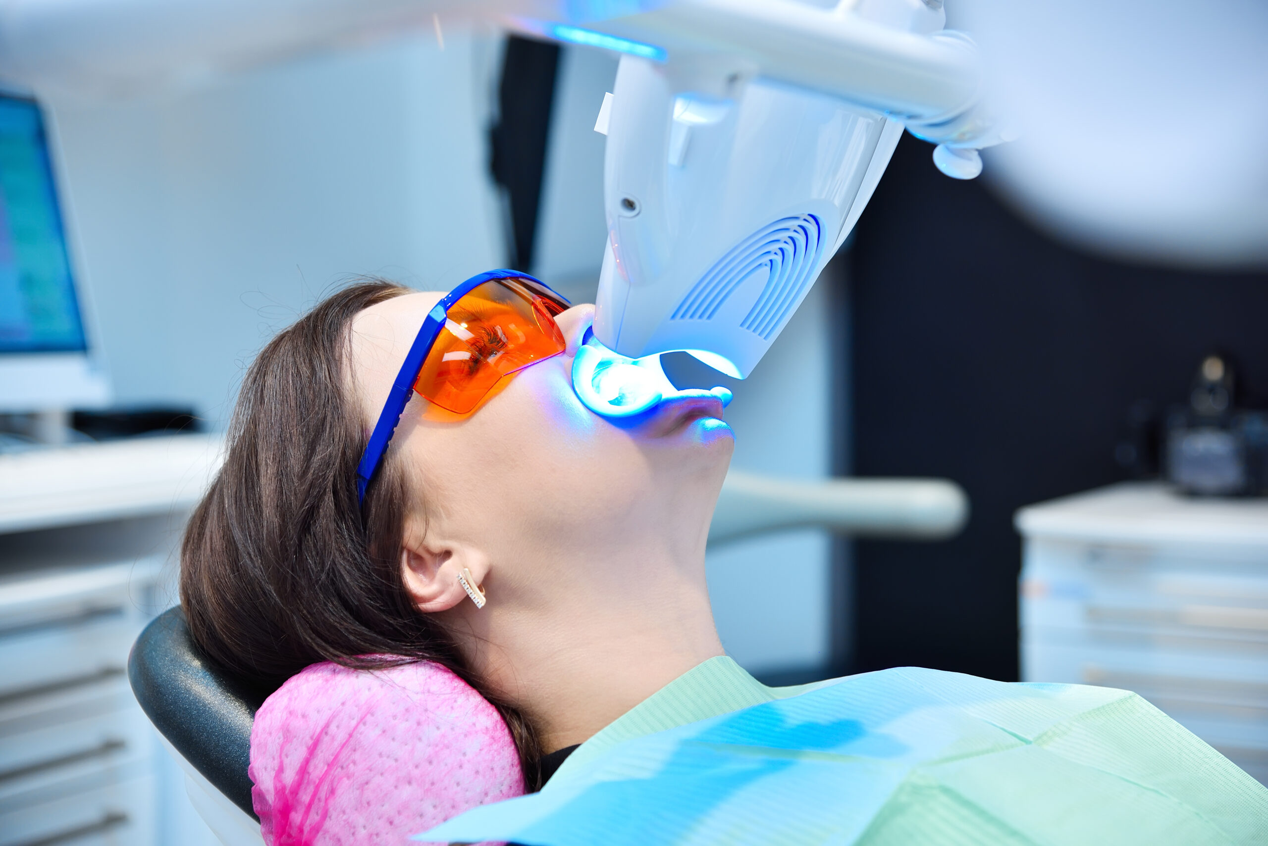 Teeth whitening for patient in protective glasses. Laser bleaching teeth in modern clinic. Whitening of teeth at dentist clinic.