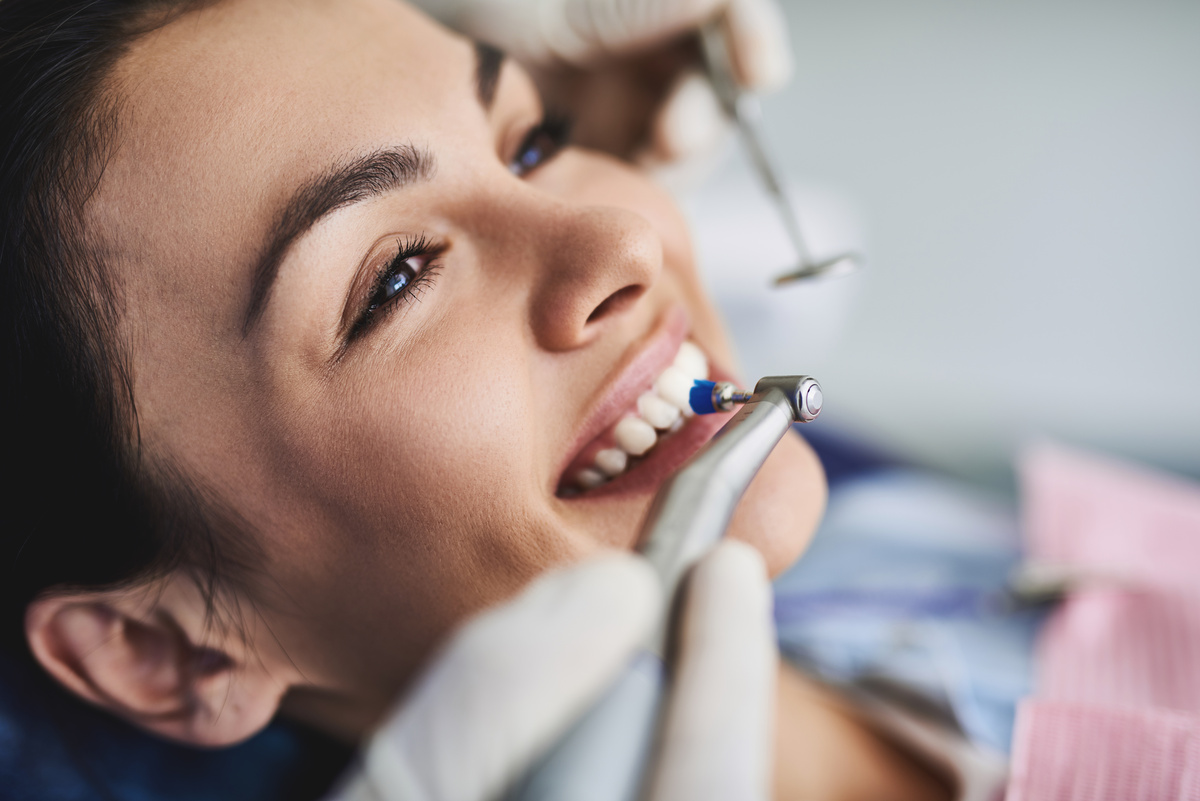 Charming young lady receiving teeth cleaning and polishing at clinic